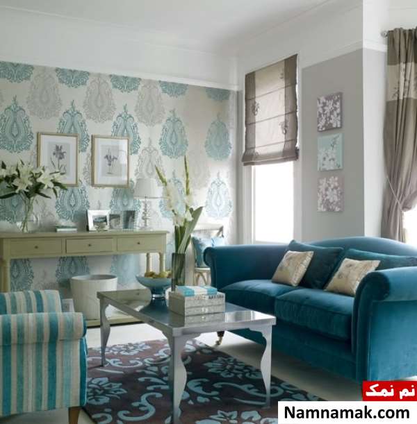 اتاق نشیمن کلاسیک با مبل های آبی رنگ که یکی از دیوارهای آن خاکستری رنگ و روی دیوار دیگر کاغذ دیواری با طرح کلاسیک نصب شده است