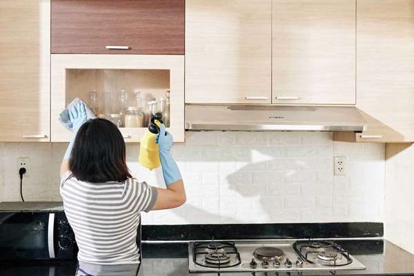 راهنمای تمیز کردن کابینت های گلاس و ترفند های جذاب و کاربردی خانومی در حال تمیز کردن کابینت های گلاس